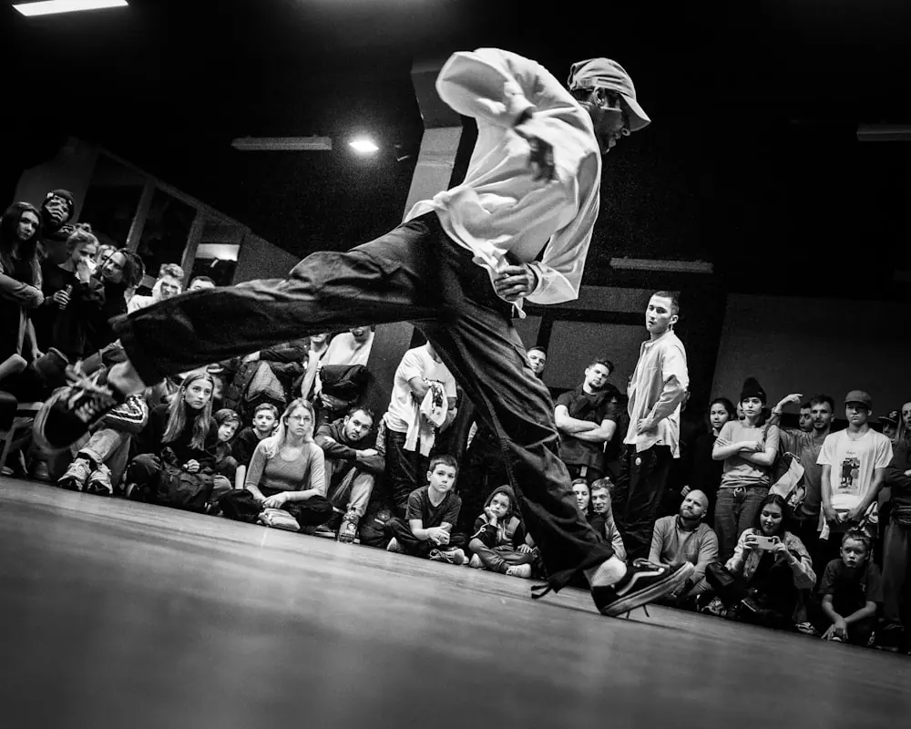 A dancer inverted mid-power-move inside a tight ring of spectators.
