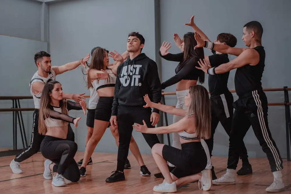 An open-level class mid-phrase in the big room, wooden floor, everyone facing a different direction.